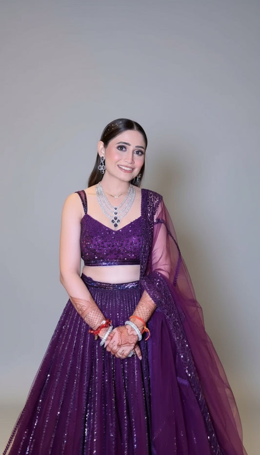 Woman in a purple traditional outfit standing in a hallway.