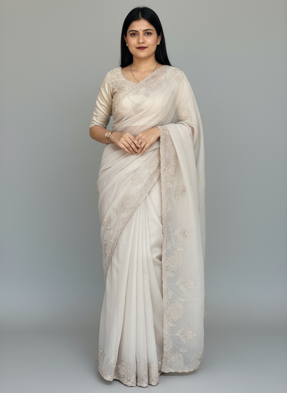 Woman wearing a white saree with lace details in an indoor setting.
