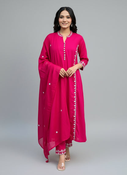 Woman wearing a bright pink traditional outfit with white buttons in an indoor setting.