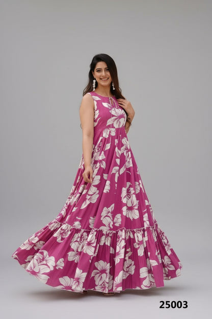 Woman wearing a pink floral dress standing outdoors with plants and a chair in the background.
