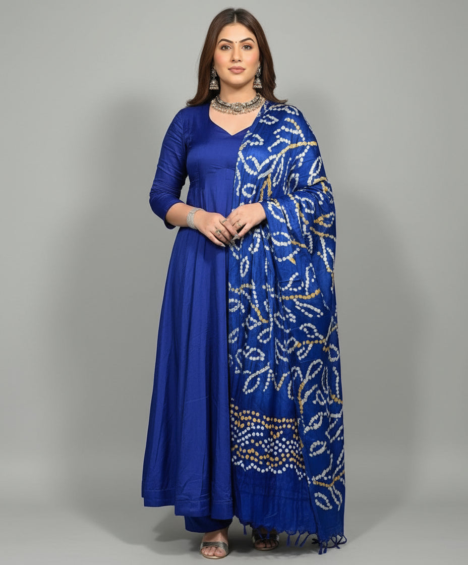 Woman wearing a blue traditional outfit with a patterned dupatta against a wooden panel background