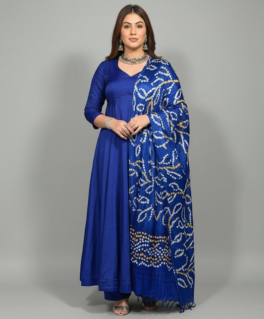 Woman wearing a blue traditional outfit with a patterned dupatta against a wooden panel background