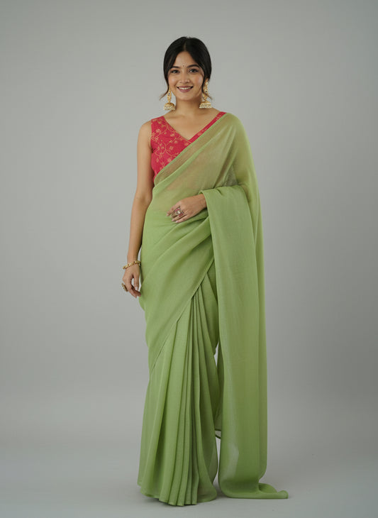 Woman wearing a green saree with a red blouse against a white background