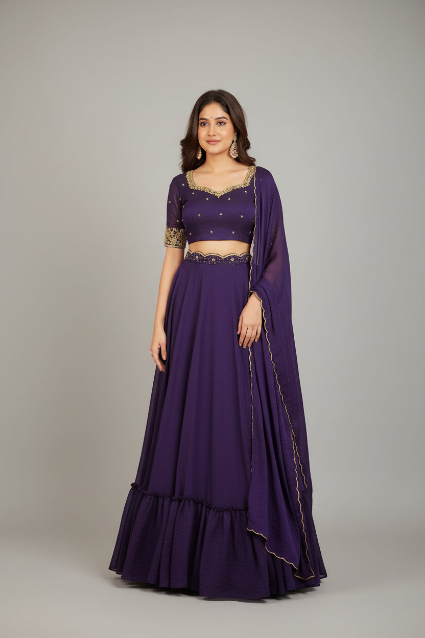 Woman in a purple traditional outfit with gold details standing in a decorated room.