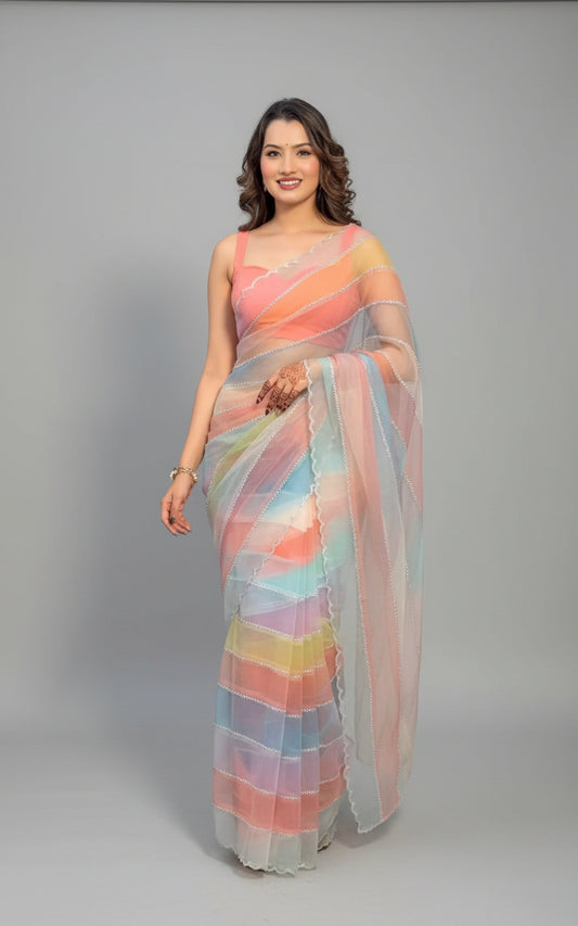 Woman in a colorful saree standing indoors with plants in the background
