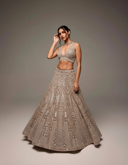 Woman wearing a traditional embroidered lehenga with a plain background