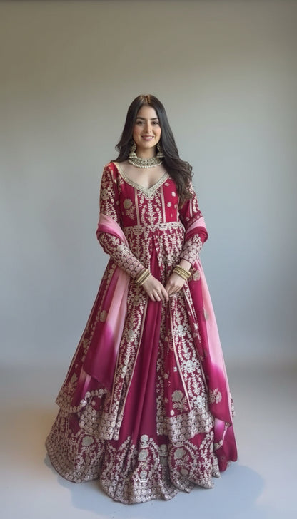 Woman in a traditional pink and red embroidered outfit indoors.