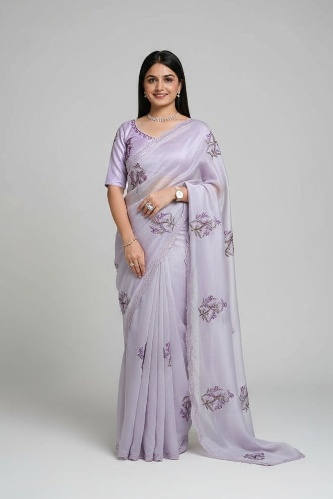 Woman in a light purple saree with floral patterns standing outdoors.