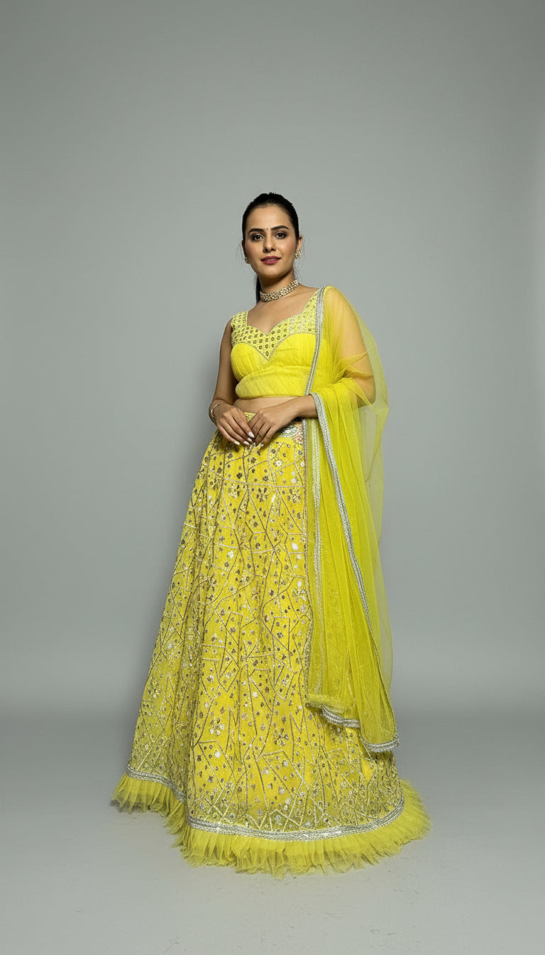 Woman in a bright yellow traditional outfit with a matching dupatta against a plain background