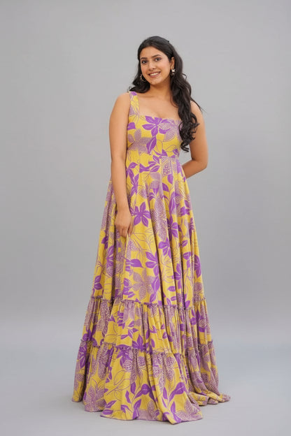 Woman in a yellow and purple floral dress standing by a pool.