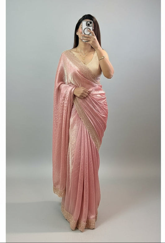Person wearing a pink saree with gold details, taking a mirror selfie.
