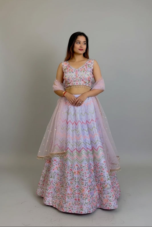 Woman in a floral dress standing in a room with blue sofas and white walls.