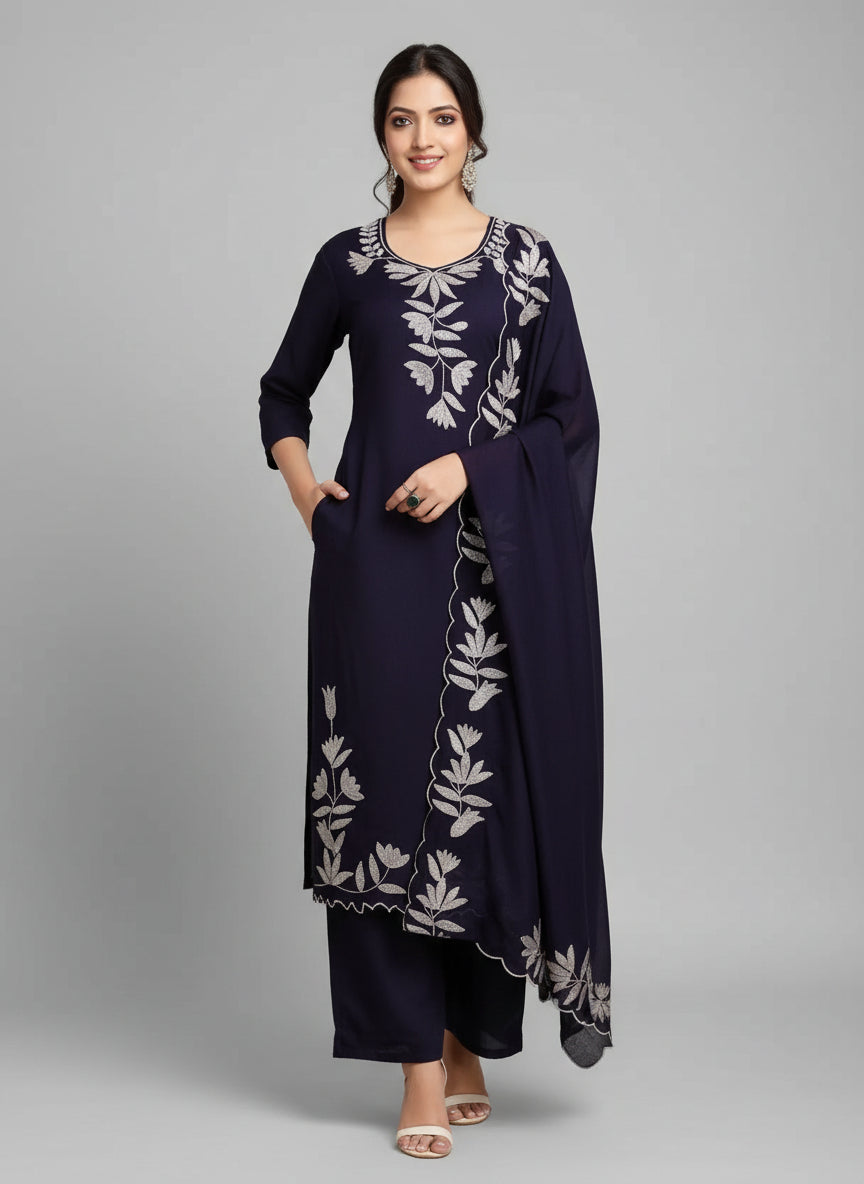 Woman wearing a navy blue outfit with white floral embroidery against an orange wall.