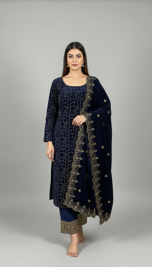 Person wearing a dark blue outfit with gold patterns, standing indoors with plants in the background.